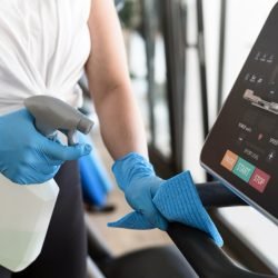 woman-with-gloves-cleaning-gym-equipment-with-solution Large